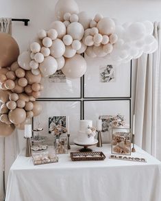 a table topped with lots of balloons next to pictures and cake on top of it