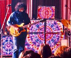 a man standing on top of a stage with a guitar in front of an audience