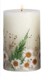 a white candle with daisies and ferns painted on the front, sitting in front of a white background