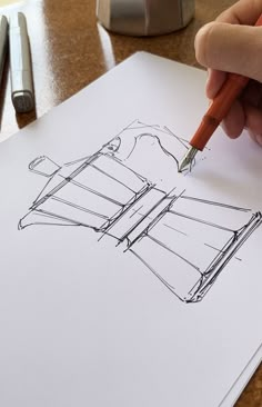 a person is drawing a dress pattern with a pencil on top of a piece of paper