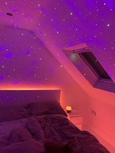 a bed sitting under a purple sky with stars on the ceiling and lights above it