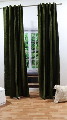 a dog sitting in front of a window with green curtains