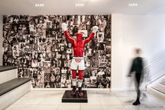 a statue of a man with boxing gloves on in front of a wall full of photos