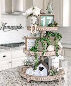 a tiered cake with flowers and plants on it's side, sitting on a kitchen counter