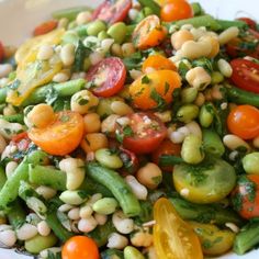 a white bowl filled with lots of veggies and beans on top of a table