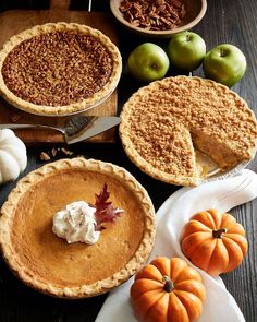 several pies, apples and pumpkins on a table