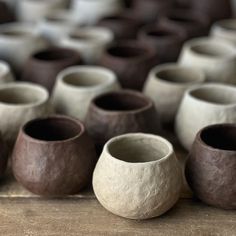 several vases sitting on top of a wooden table covered in brown and white clay