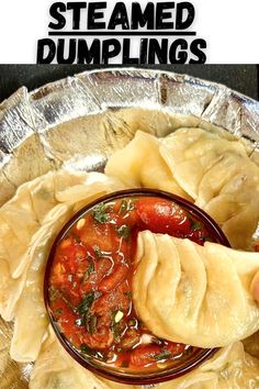 a person dipping sauce on top of dumplings in a metal bowl with text overlay