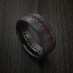 a black ring with red stones in it on a wooden surface and dark wood floor