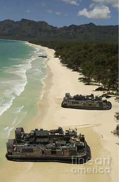 two large boats are on the beach next to the ocean