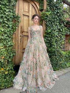 a woman standing in front of a wooden door wearing a dress with flowers on it