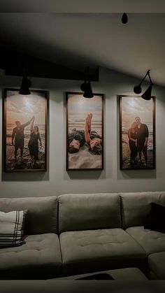 three pictures hang on the wall above a couch in a living room with two people