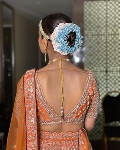 the back of a woman's dress with flowers in her hair and an elaborate headpiece