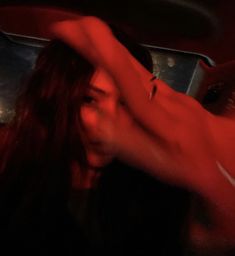 a woman with long hair standing in front of a red light