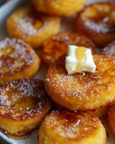 some sugared donuts are sitting on a plate with butter and powdered sugar