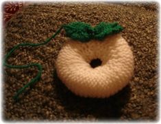 a crocheted donut with a green bow on it's head sitting on the carpet