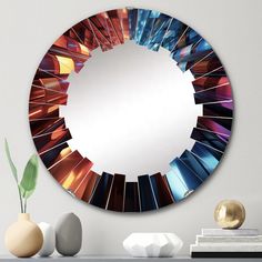 a round mirror with many different colors in the frame on a table next to vases