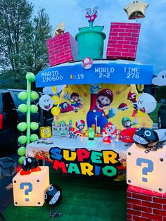 a super mario themed birthday party with balloons and decorations on the grass, including an inflatable cake stand