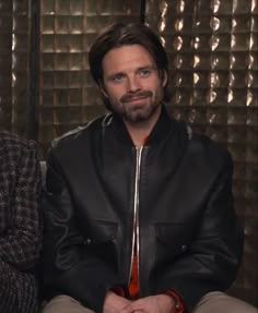 a man in a leather jacket sitting down