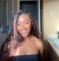 a woman with long hair standing in front of a bathroom mirror and smiling at the camera