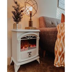 a white stove sitting next to a couch in a living room with a lamp on top of it