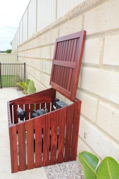 an open wooden box sitting on the side of a building next to a planter