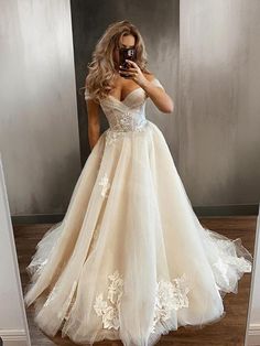 a woman in a wedding dress taking a selfie with her cell phone while standing in front of a mirror