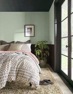 a bed sitting in a bedroom next to a window with a potted plant on top of it