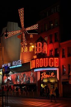 a street scene at night with people walking on the sidewalk and buildings in the background