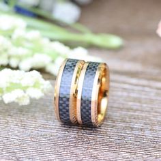 two tone gold and black wedding rings with carbon fiber inlays, set on a bamboo mat