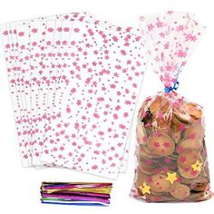 pink and white stars are in a bag next to some paper napkins with gold stars on them