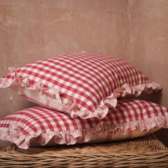 two red and white checkered pillows sitting on top of a wicker basket