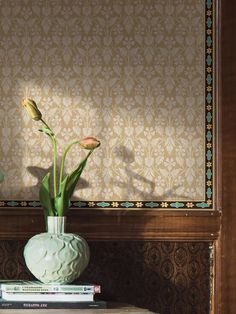 two tulips in a vase sitting on top of a table next to books