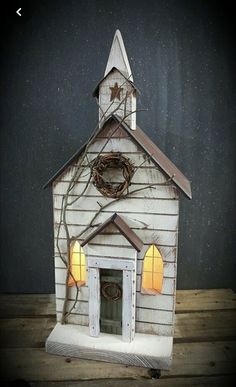 a small white church with a clock on the front and side windows, is lit up at night