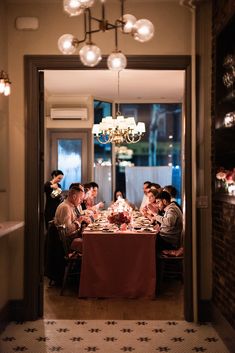 a group of people sitting at a table in a room with chandeliers hanging from the ceiling