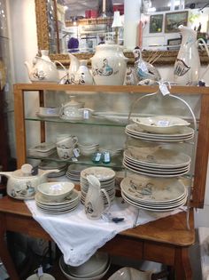 a display case filled with lots of plates and bowls on top of a wooden table