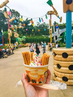 a person holding up an ice cream sundae with waffle fries in front of them