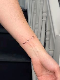 a person's arm with a small heart tattoo on the left side of their wrist