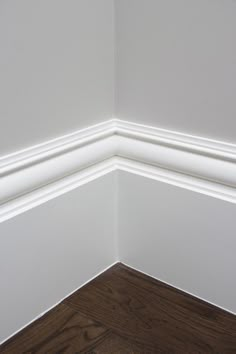 the corner of a room with white walls and wood flooring