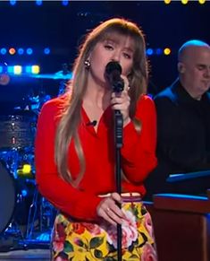 a woman standing in front of a microphone on top of a stage