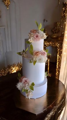 a three tiered wedding cake with flowers on top