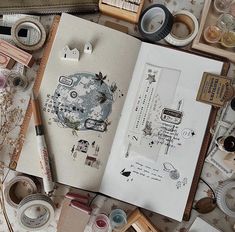 an open book on top of a table filled with crafting supplies and paper goods