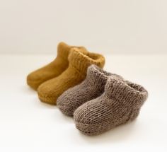 three pairs of knitted baby booties on a white surface