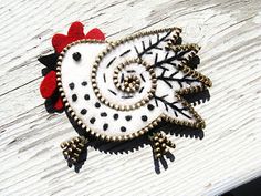 a white and black brooch sitting on top of a piece of wooden planks