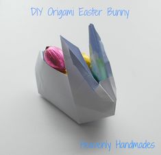 an origami easter bunny in a paper bag with colored eggs inside and the words diy organi easter bunny above it