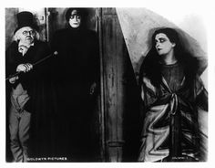 an old black and white photo of two people dressed as witches, one holding a broom