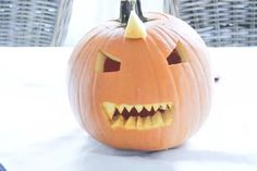 a carved pumpkin with sharp teeth on it's face and mouth is sitting on a table