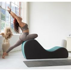 a woman is doing yoga on an exercise ball in front of a window with her legs up