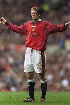 a man standing on top of a soccer field holding his arms out to the side