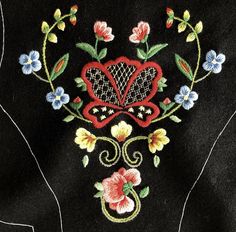 a hand embroidered with flowers and leaves on black fabric, showing the heart surrounded by floral designs